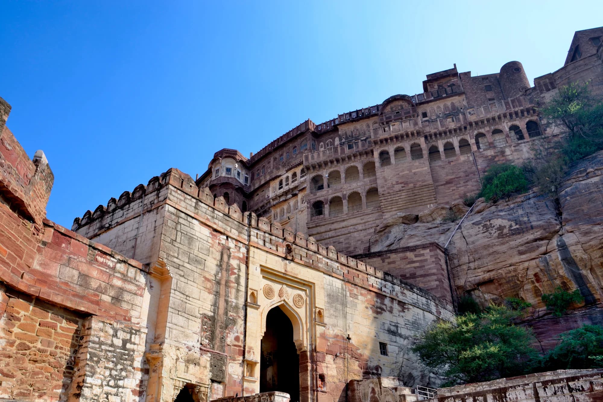 Mehrangarh Fort, Jodhpur — the 560-year-old citadel rising from a 400-foot basalt cliff above RAAS Jodhpur, its golden sandstone ramparts floodlit at dusk against a violet desert sky