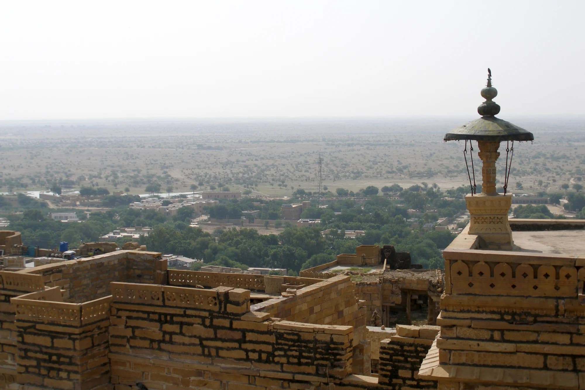 The Library bar — walls lined with books on Rajasthani history, leather armchairs, a cocktail called The Mirage catching the light from a brass lantern, the sandstone walls glowing amber