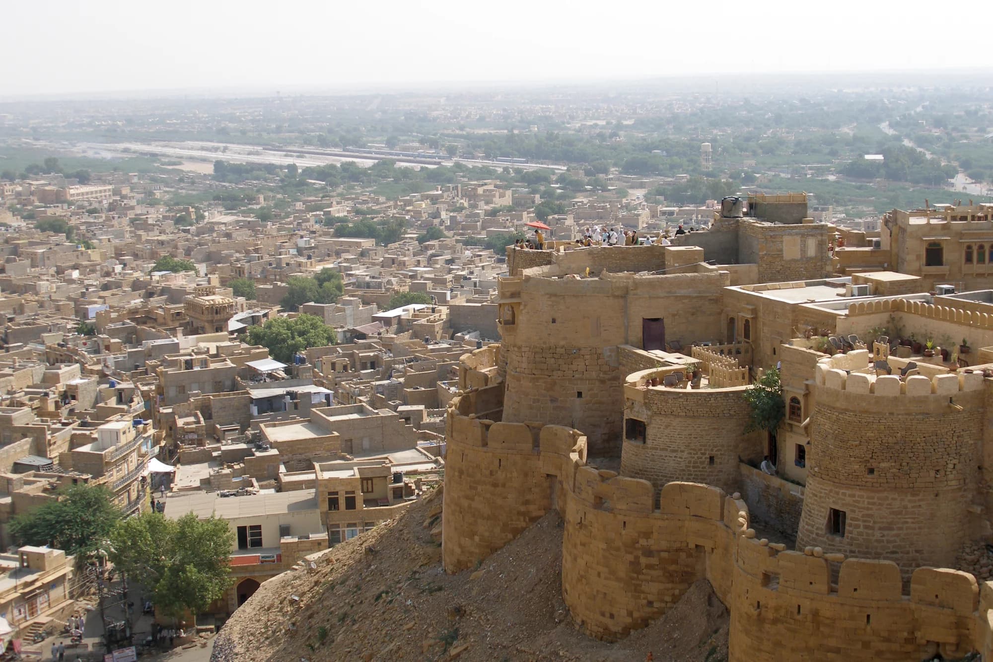 The abandoned village of Kuldhara at sunset — empty stone houses and temples stretching toward the horizon, long shadows crossing abandoned courtyards, the silence broken only by the desert wind