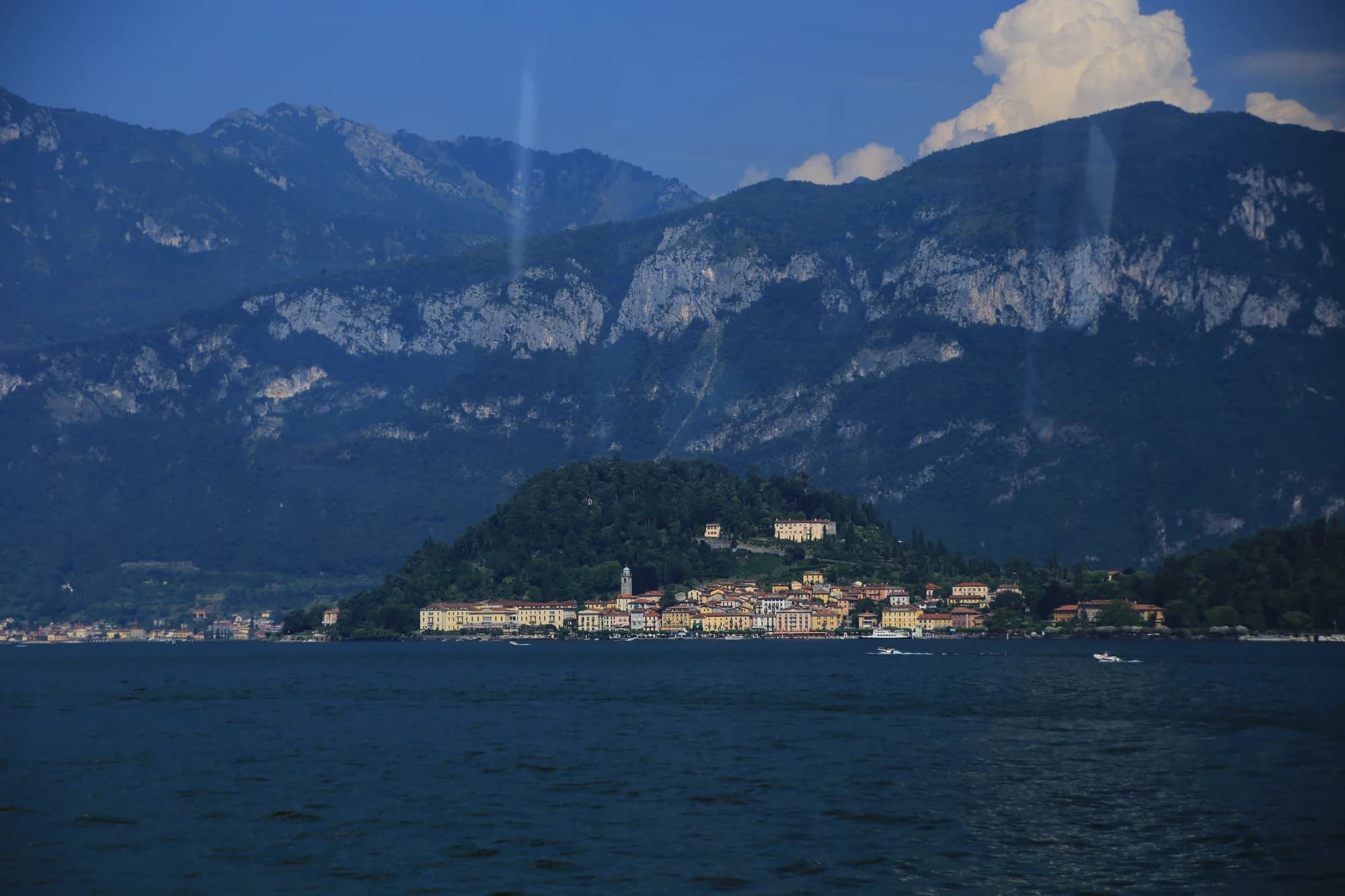 Lake Como at dusk from a Riva boat, the villas and mountains reflected in water like glass