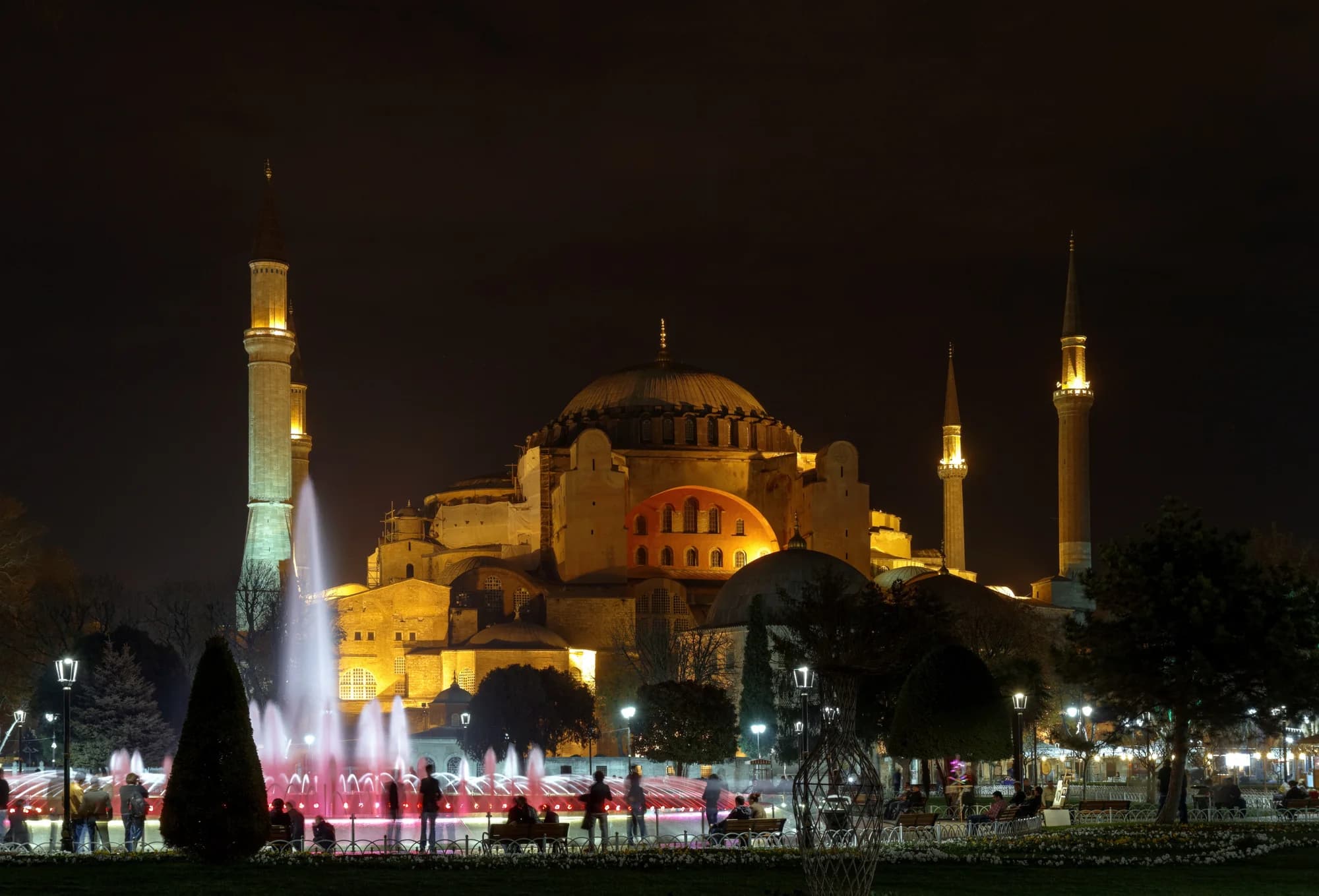 The interior of a historic hamam — star-shaped perforations casting shafts of light through steam onto white marble, a tellak pouring water from a copper tas, the göbek taşı gleaming beneath the domed ceiling