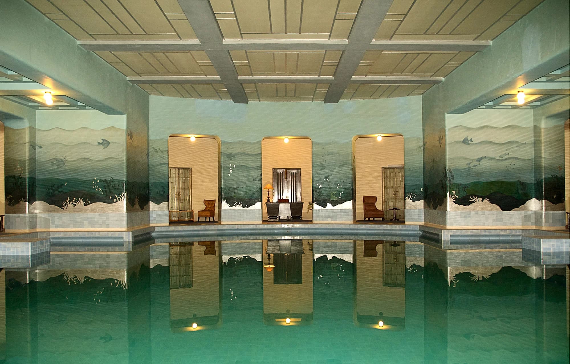 The swimming pool at Umaid Bhawan — an azure rectangle set into emerald lawns, flanked by classical stone pavilions, the palace dome rising majestically beyond