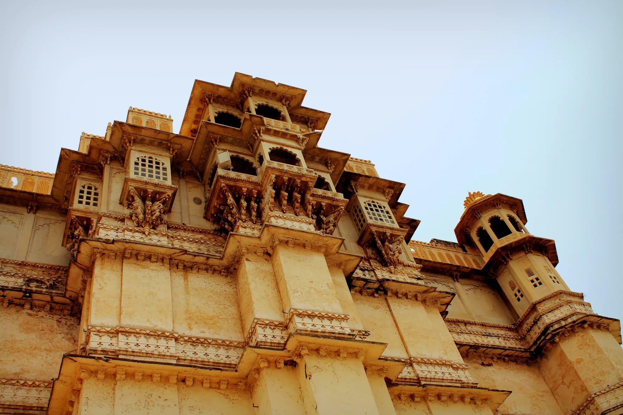 A Devi Garh suite — walls of exposed 18th-century stone meeting floors of white marble, a bed dressed in white linen the only object in a chamber of cathedral-like proportions, a single window framing the Aravalli Hills