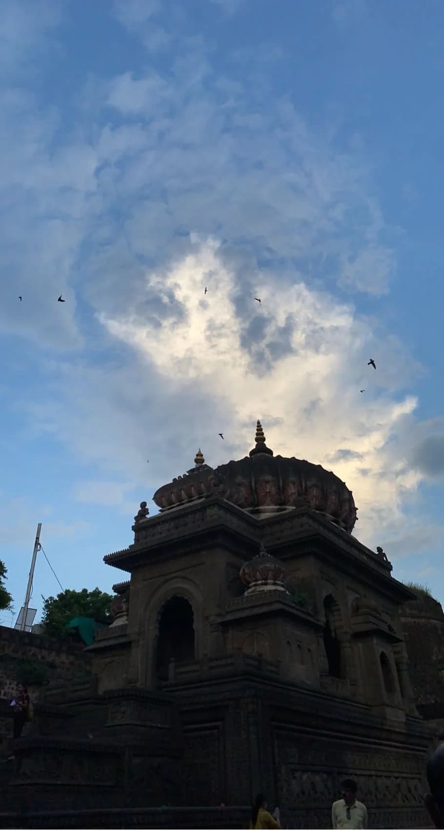 Ahilya Fort from the Narmada River at dawn — the eighteenth-century ramparts rising from the water's edge, temple spires silhouetted against a pink sky, the sacred river already alive with pilgrims and prayer