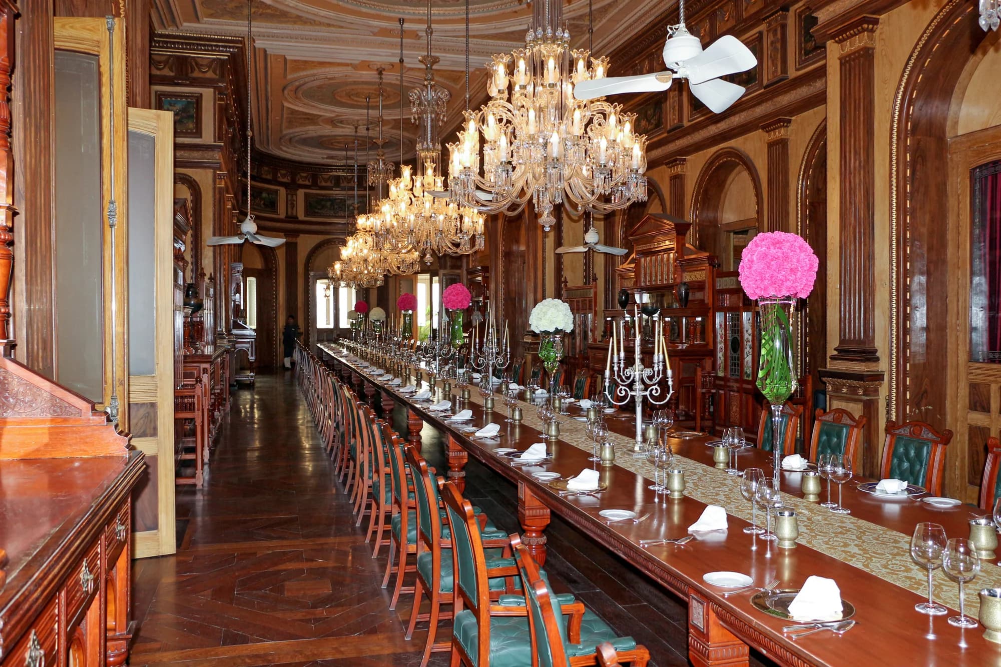 The walnut-ceilinged library — a faithful replica of Windsor Castle's reading room, 6,000 volumes lining carved gallery shelves, afternoon light filtering through stained glass onto leather-bound spines