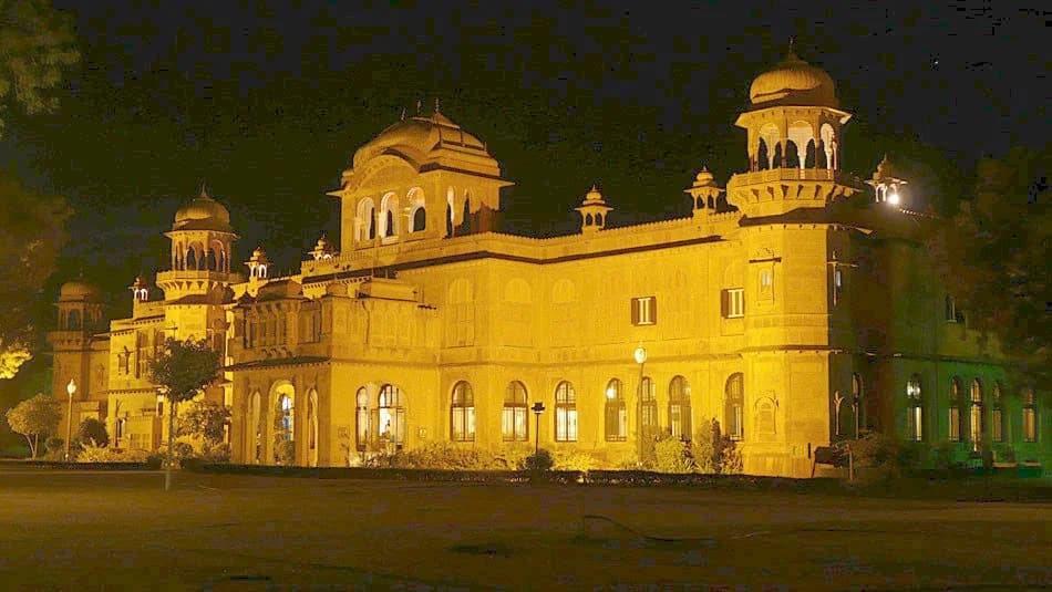 The central facade — three storeys of carved red sandstone rising above formal reflecting pools, jharokha balconies and jali screens creating a composition of light, shadow, and intricate geometric pattern